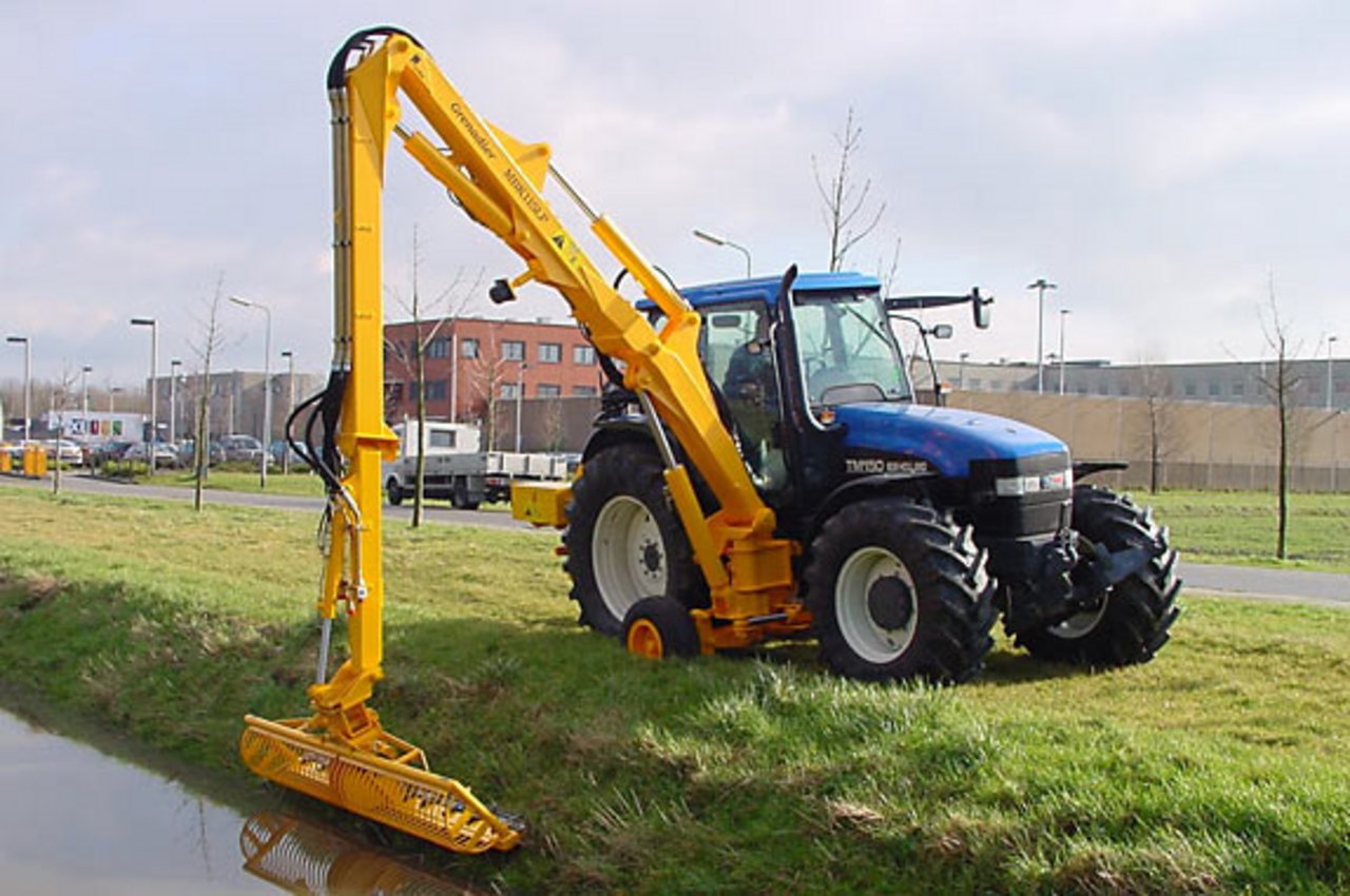 Traktor mit Mähkorb am Ufer
